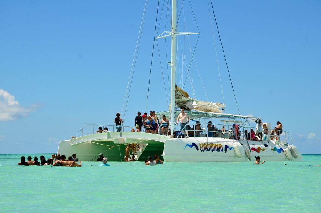 Catamaran and travelers in shallow Caribbean water